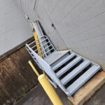 Custom steel access stairs and safety handrails installed at a commercial building service entrance.
