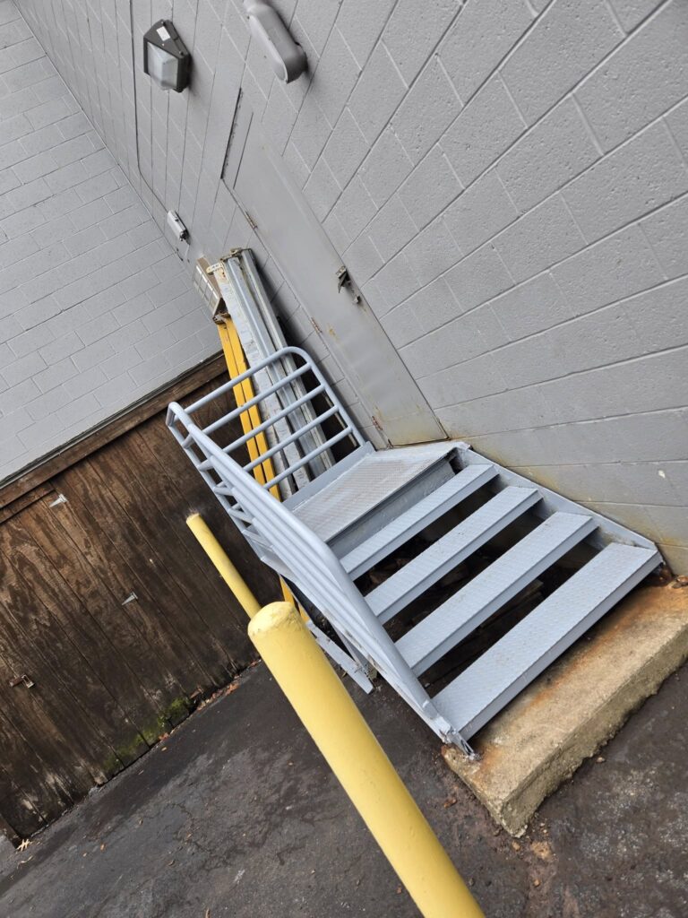 Custom steel access stairs and safety handrails installed at a commercial building service entrance.