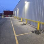 Commercial safety guardrail installation along a warehouse exterior to protect building walls and loading area traffic.