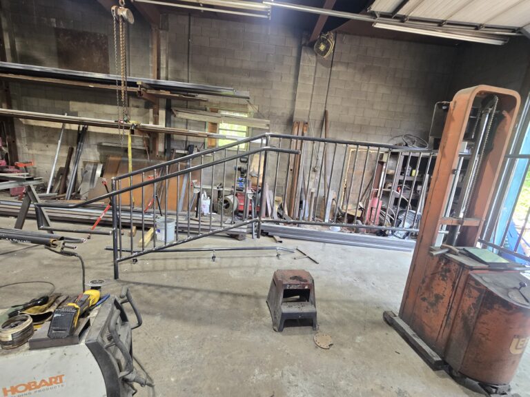 Custom steel handrail fabrication and welding project in a metal fabrication shop for commercial stair access systems.