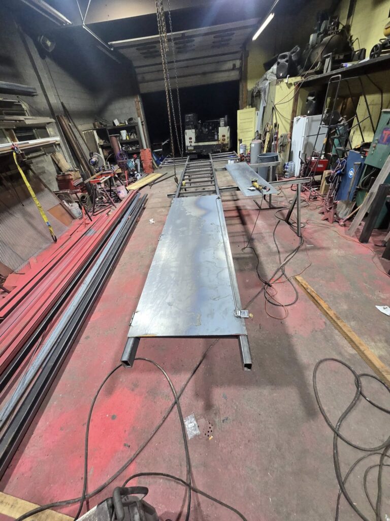 Custom steel loading ramp and equipment platform under fabrication in a Pennsylvania welding shop.