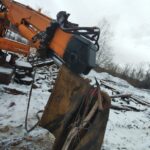 Heavy equipment bucket repair and welding service performed on an excavator attachment for industrial construction equipment.