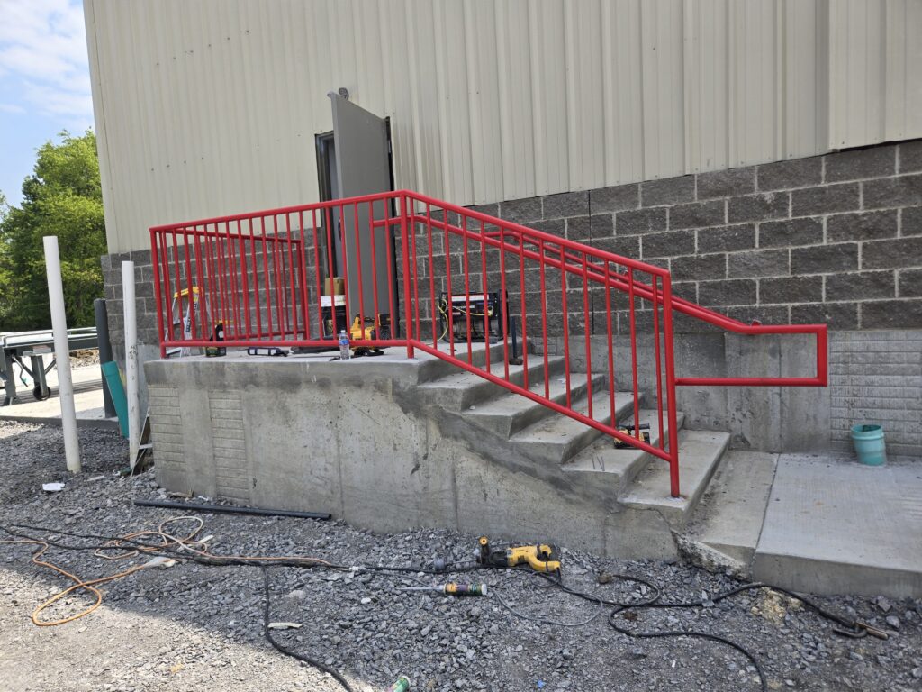 Red steel safety handrail installed on commercial concrete stairs