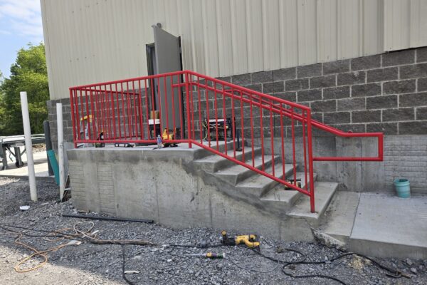 Red steel safety handrail installed on commercial concrete stairs