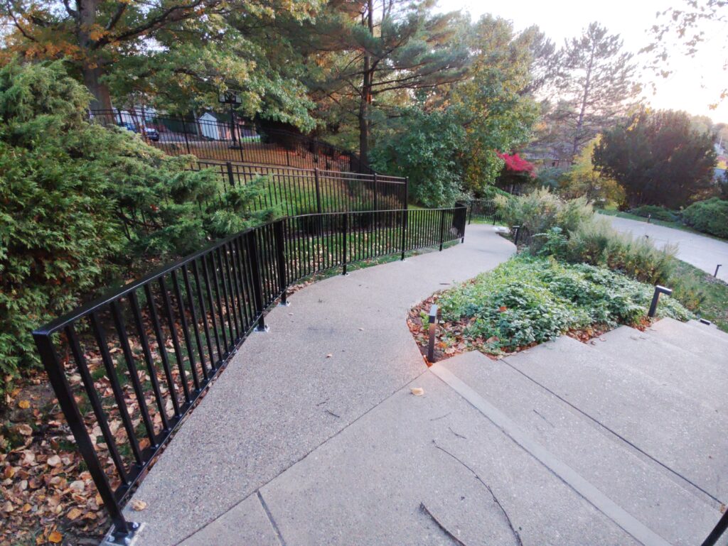 Custom black steel railing installed along outdoor walkway path