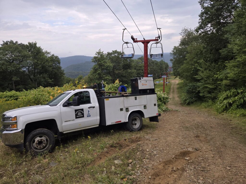 Mobile welding service truck performing repair work near ski lift structure