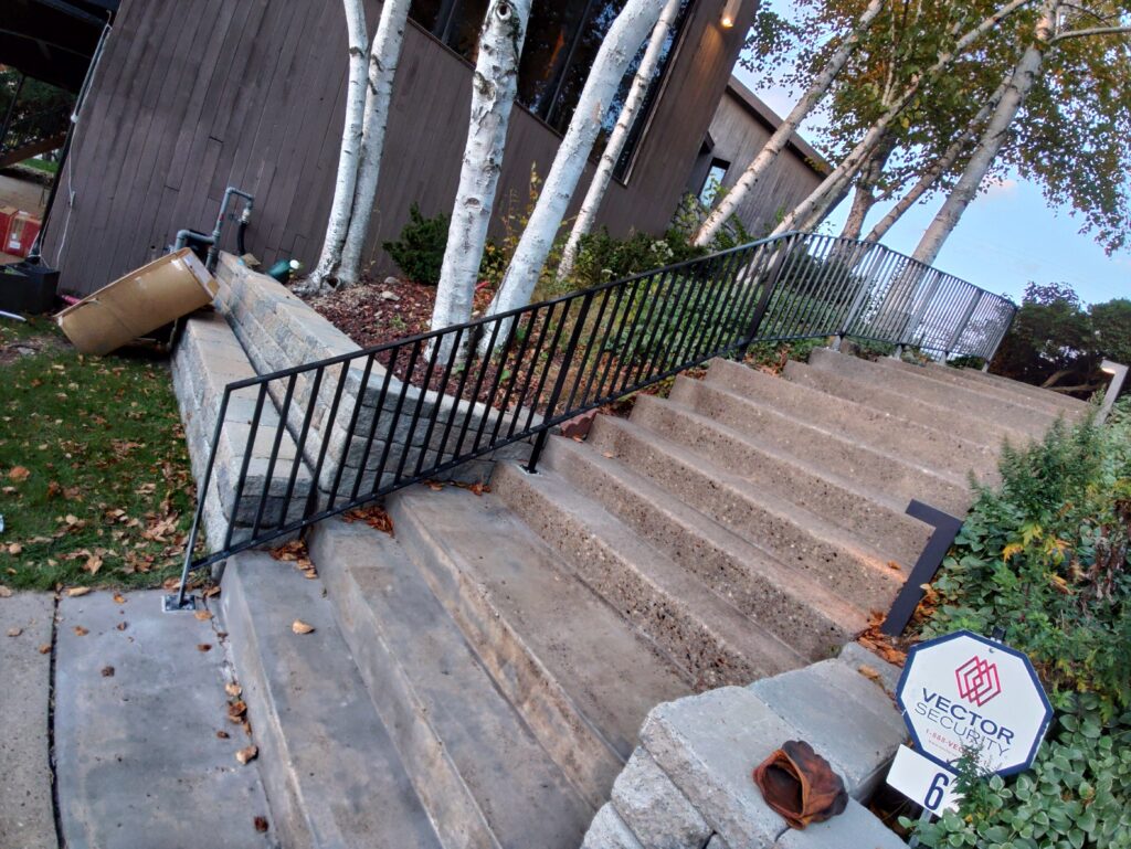 Custom steel stair railing installed along outdoor concrete steps