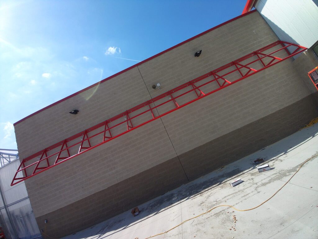 Red structural steel support frame installed on commercial building exterior