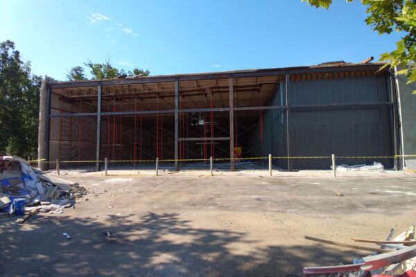 Commercial building expansion featuring custom structural steel framing and large clear span opening under construction.