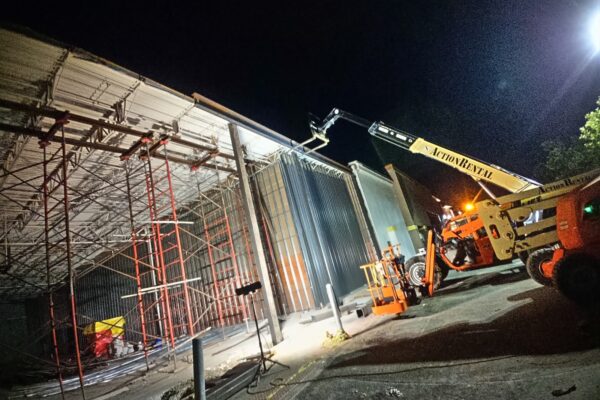 Commercial building expansion with structural steel installation and aerial lift during nighttime construction work in Pennsylvania.