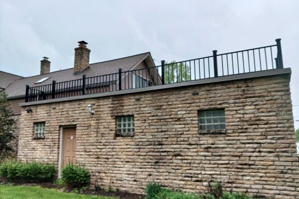 Custom steel rooftop guardrail system installed on a stone commercial building for fall protection and safety compliance.