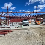 Commercial steel building frame construction with structural columns and roof joists installed for a large fabrication project.