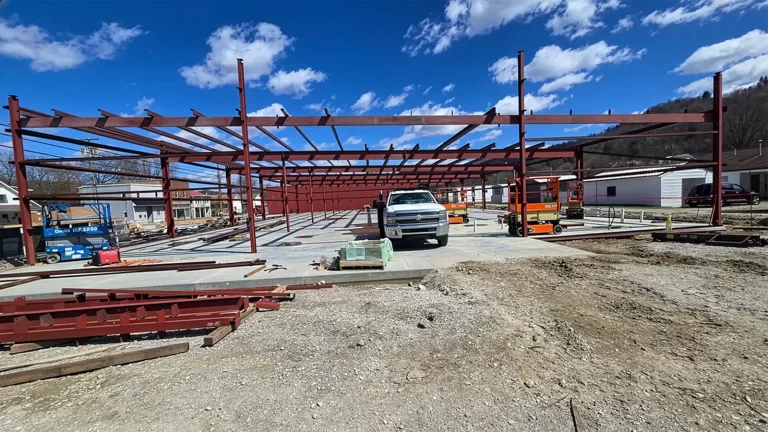 Commercial steel building frame construction with structural columns and roof joists installed for a large fabrication project.